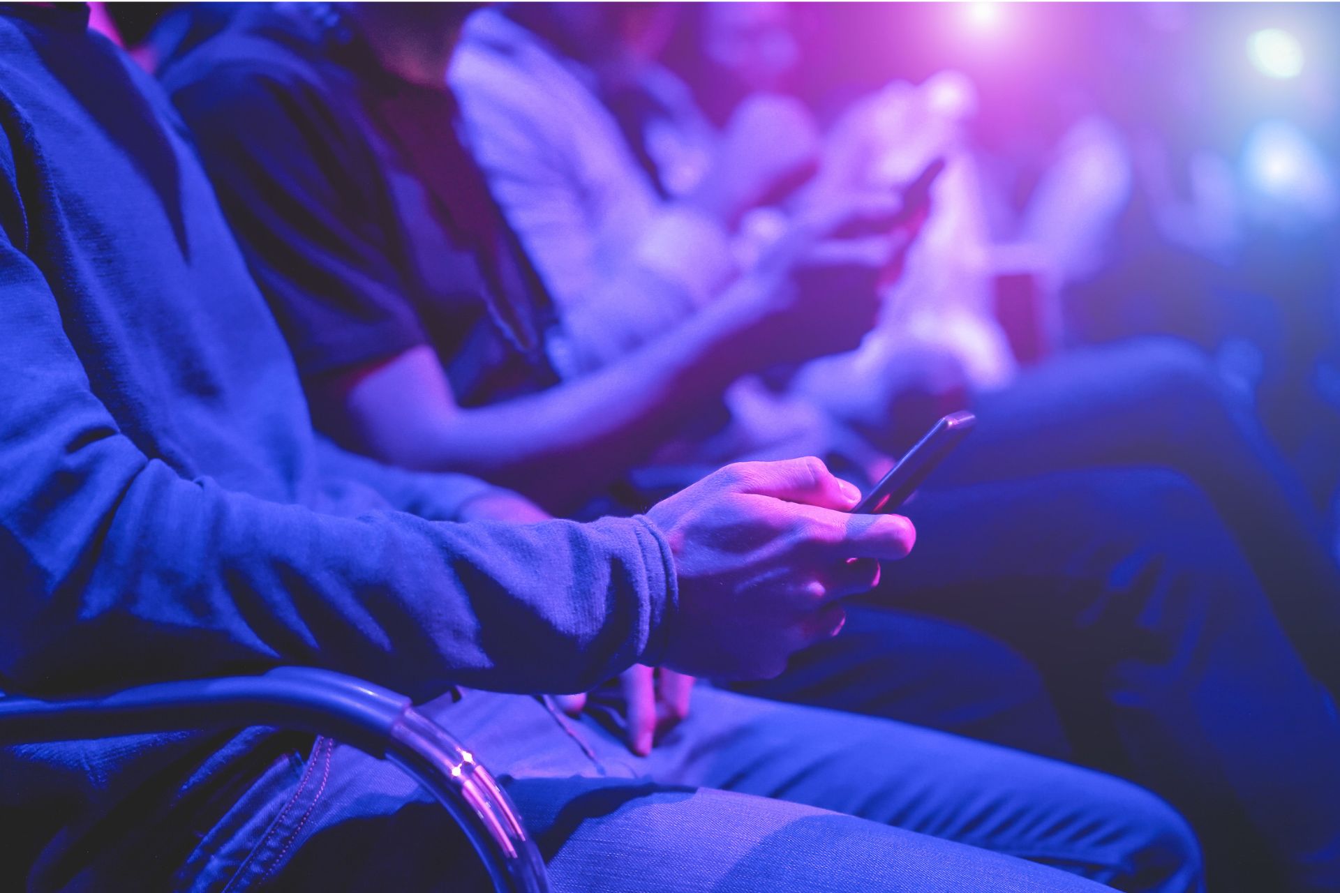 Audience members using phones during a live experience with blue and purple lights