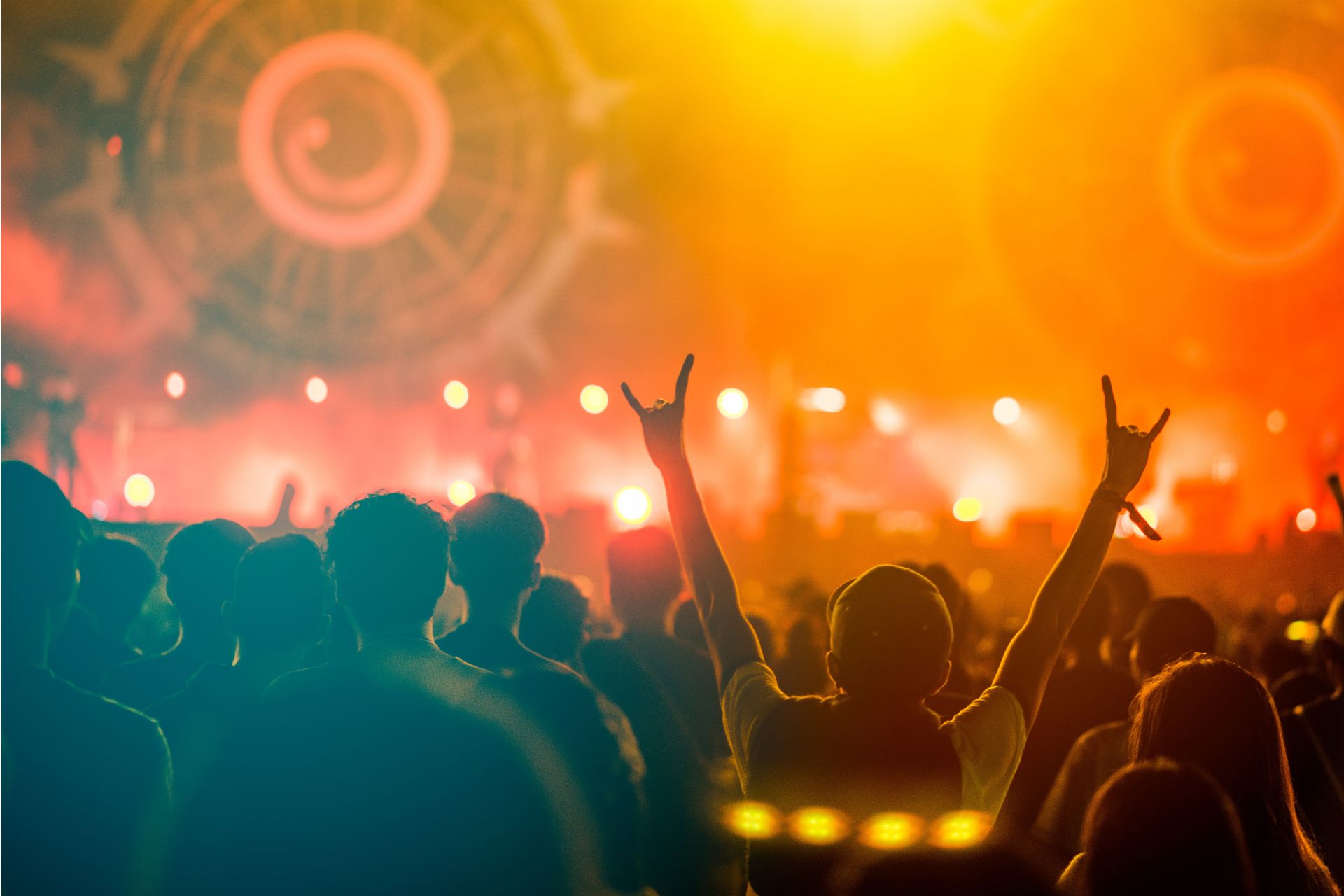 Crowd at a live concert with warm amber stage lights and raised hands